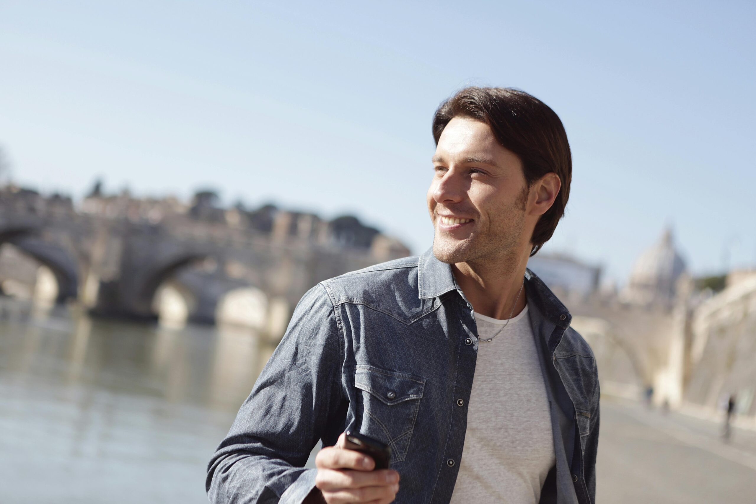 Man In Denim Jacket Holding A Black Smartphone
